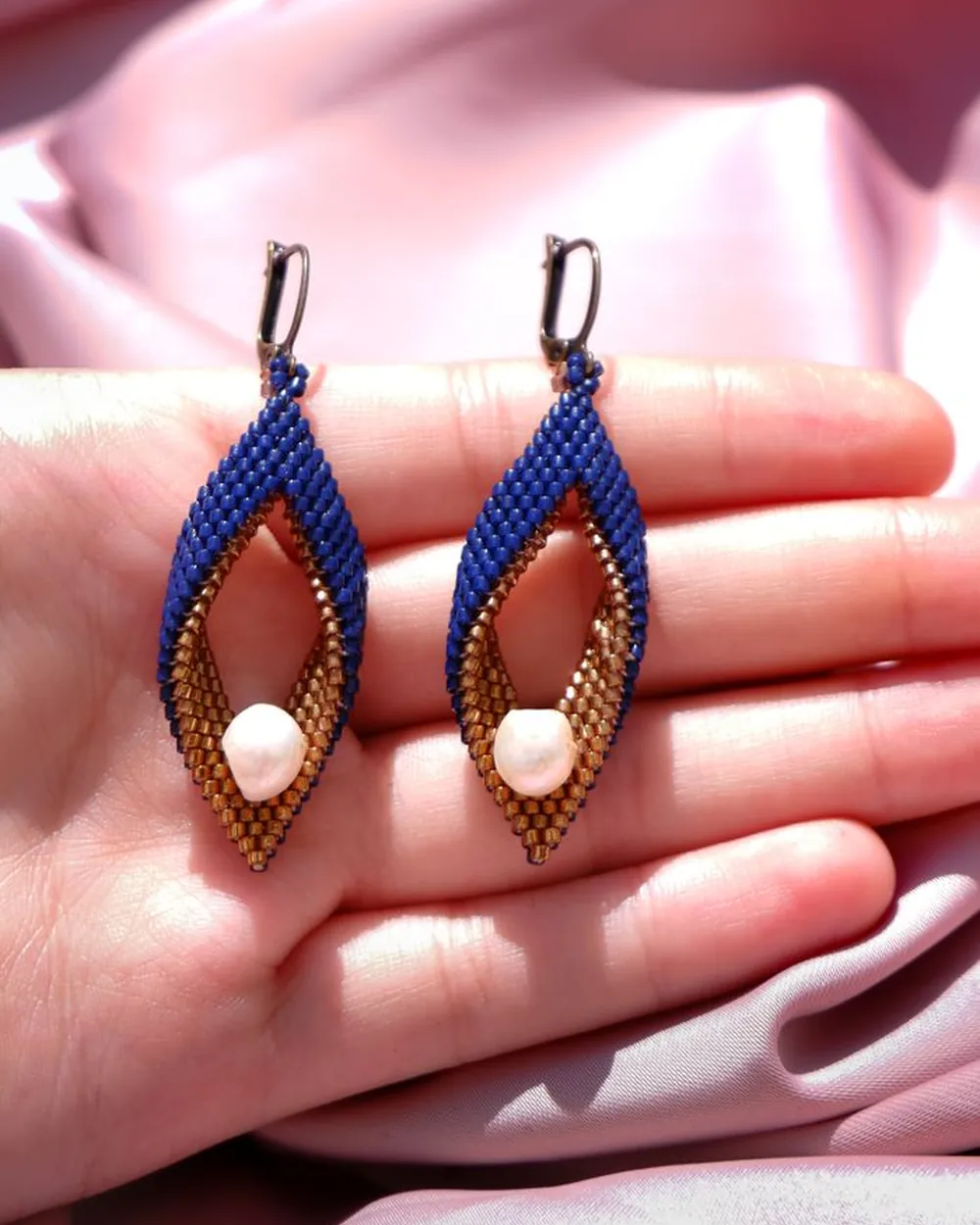 Boucles d'oreilles perlées en forme de navette, présentées dans une main