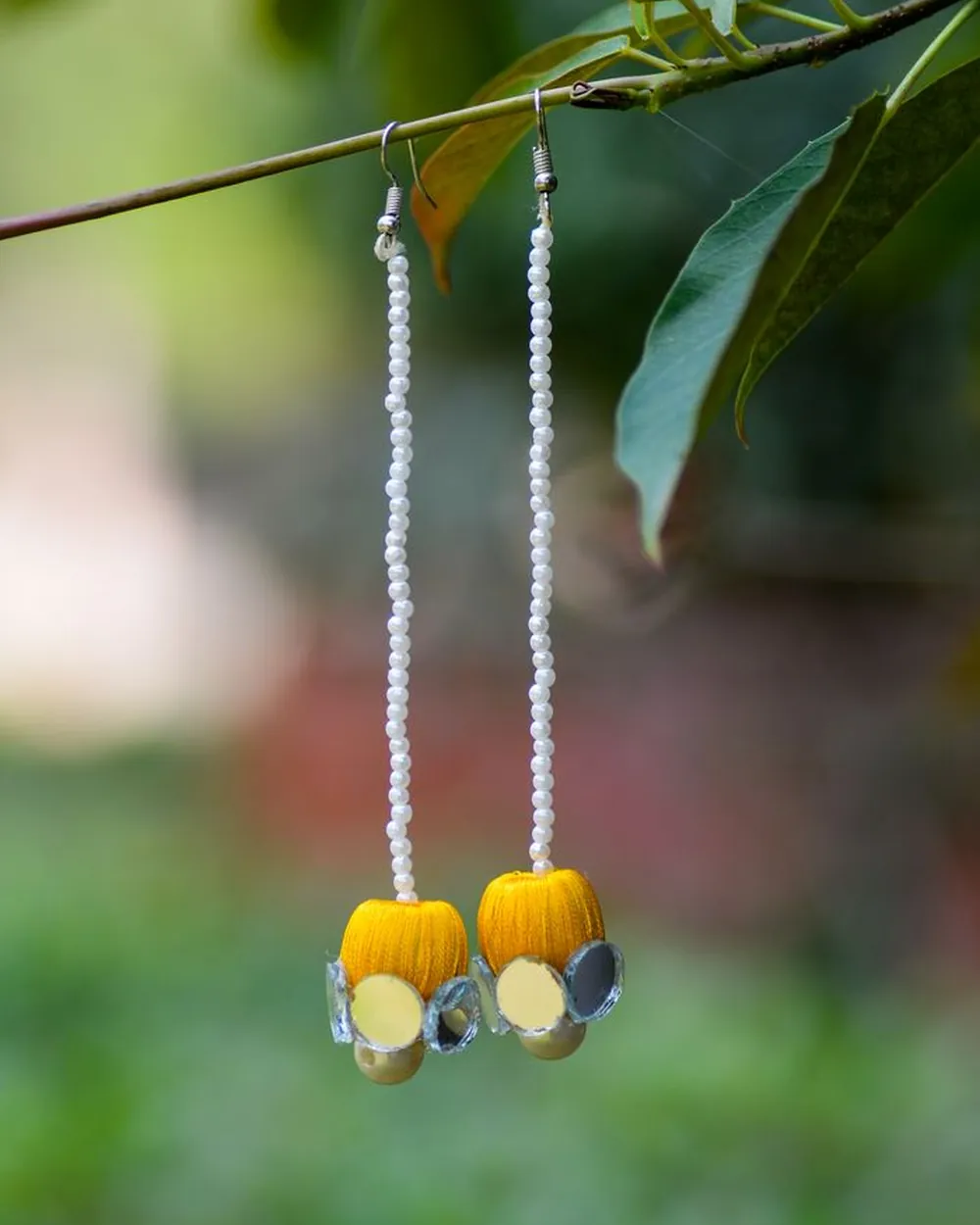 Longues boucles d'oreilles perlées suspendues à une branche