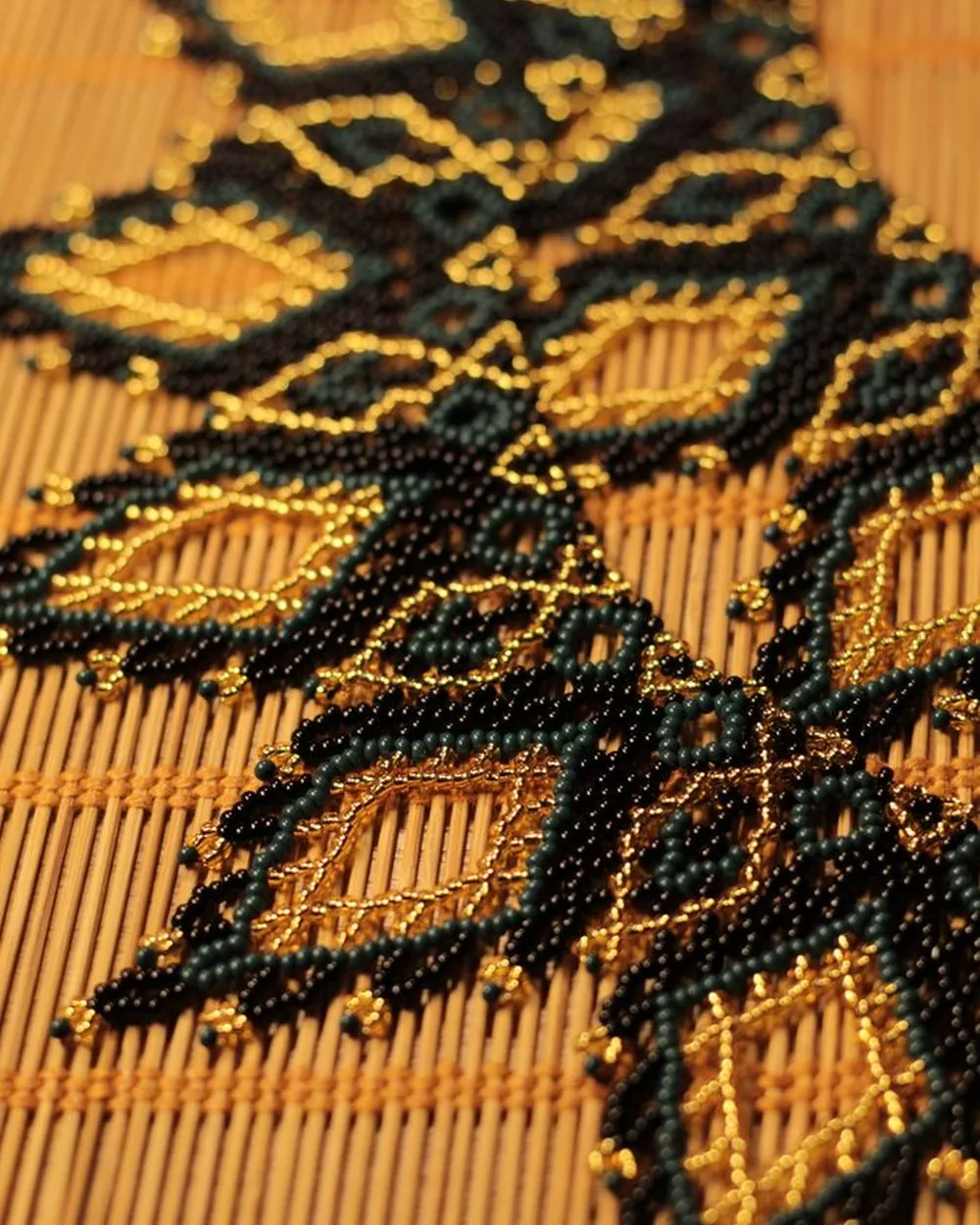 Détail d'un collier perlé noir et or à motifs géométriques