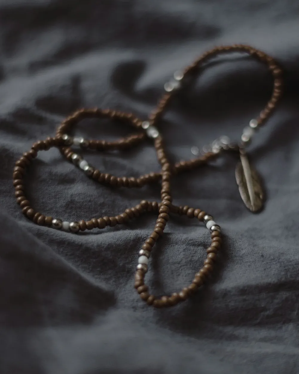 Long sautoir de petites perles posé sur un tissu sombre